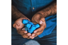 Hands holding blue coffee capsules.